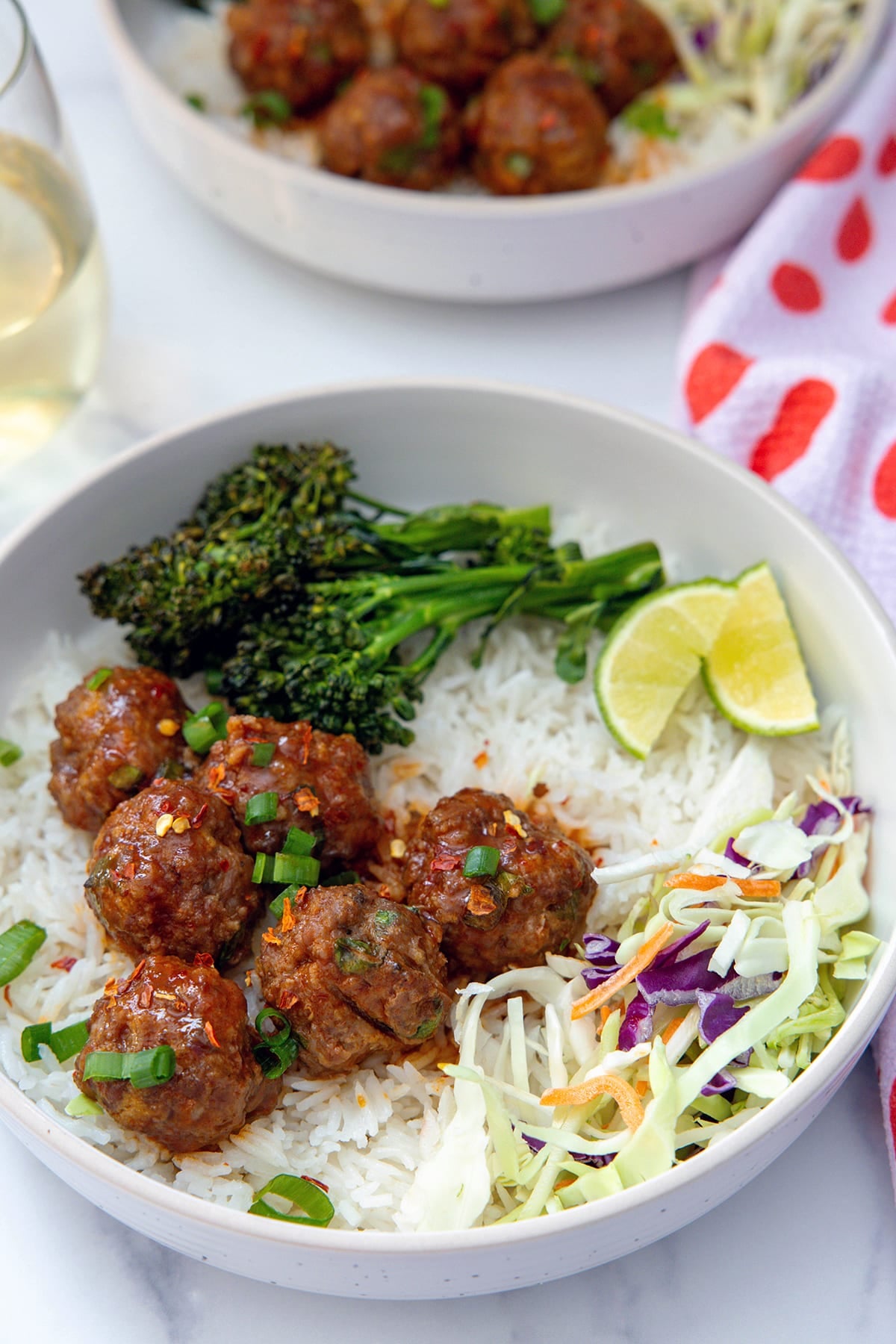 Overhead view of a plate of coconut rice, spicy and sweet meatballs, slaw, and broccolini.