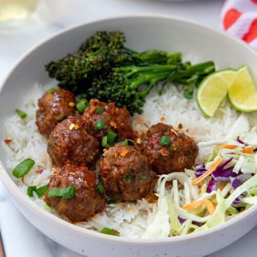 Closeup view of spicy and sweet meatballs over coconut rice.