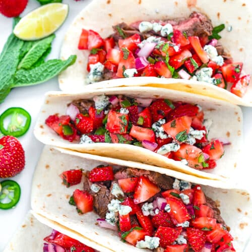 Closeup overhead view of flank steak tacos with strawberry mint salsa and crumbled gorgonzola.