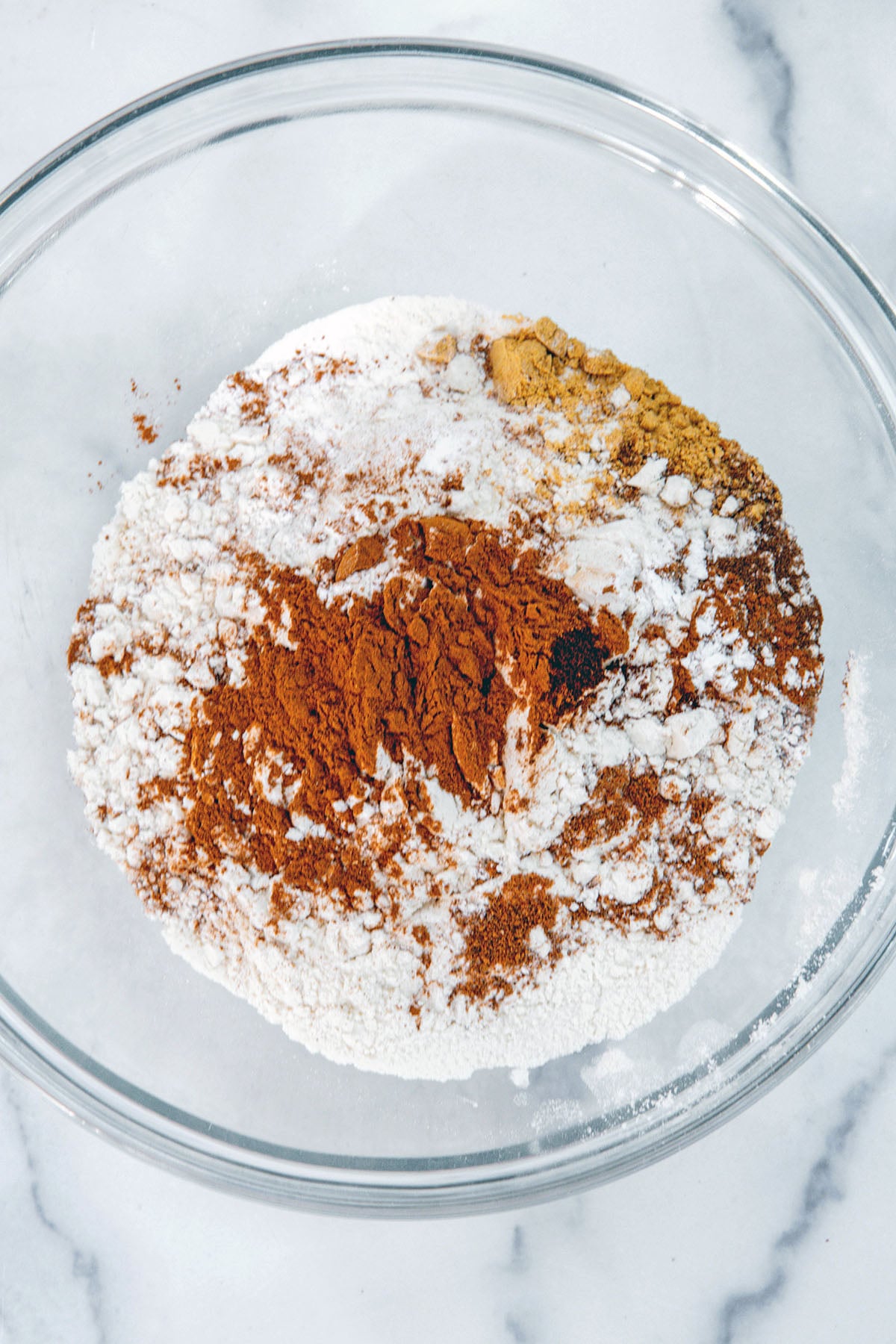 Overhead view of flour and spices in mixing bowl.