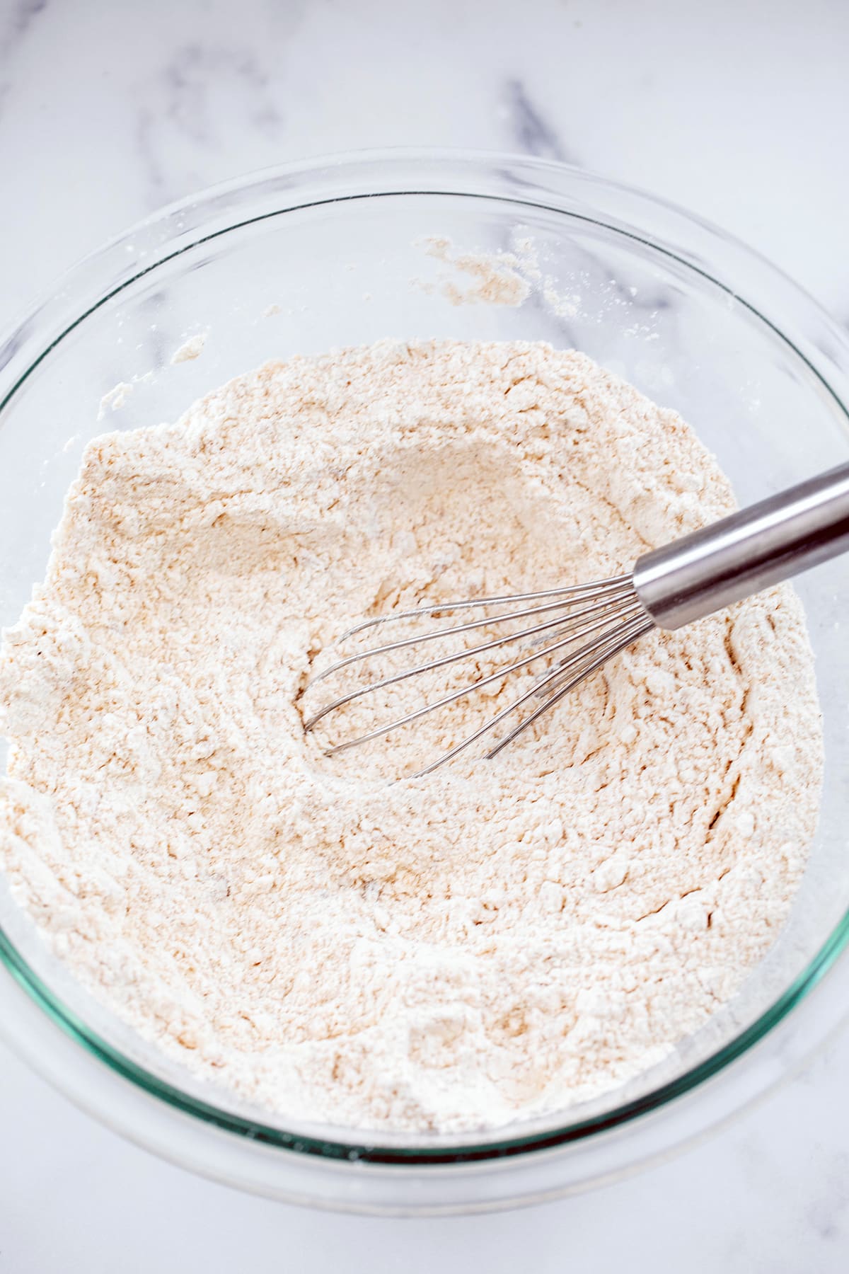 Dry ingredients mixed together in bowl with whisk.