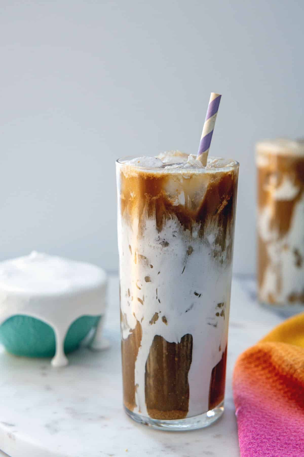 Head-on view of a Fluffy Seagull coffee drink in a fluff-lined glass with second drink and bowl of fluff in background.