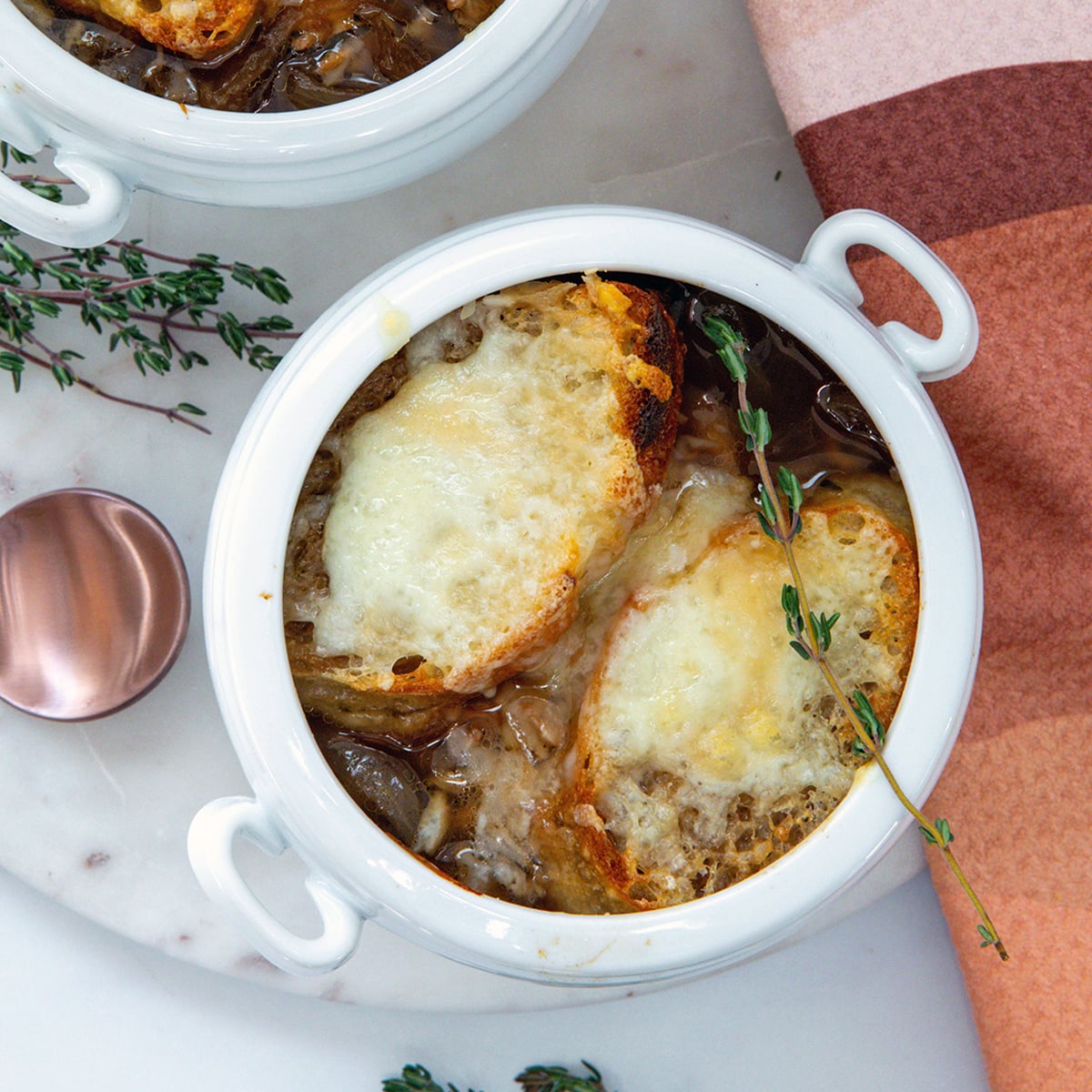 Closeup overhead view of french onion chicken soup with croutons and melted cheese.