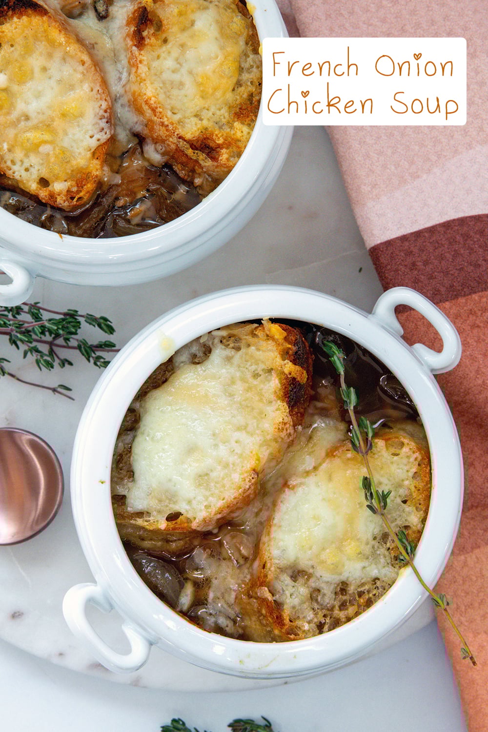 Overhead view of two bowls of french onion chicken soup with thyme all around and recipe title at top.