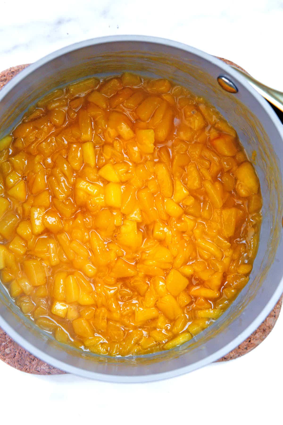Fresh peach filling in saucepan.