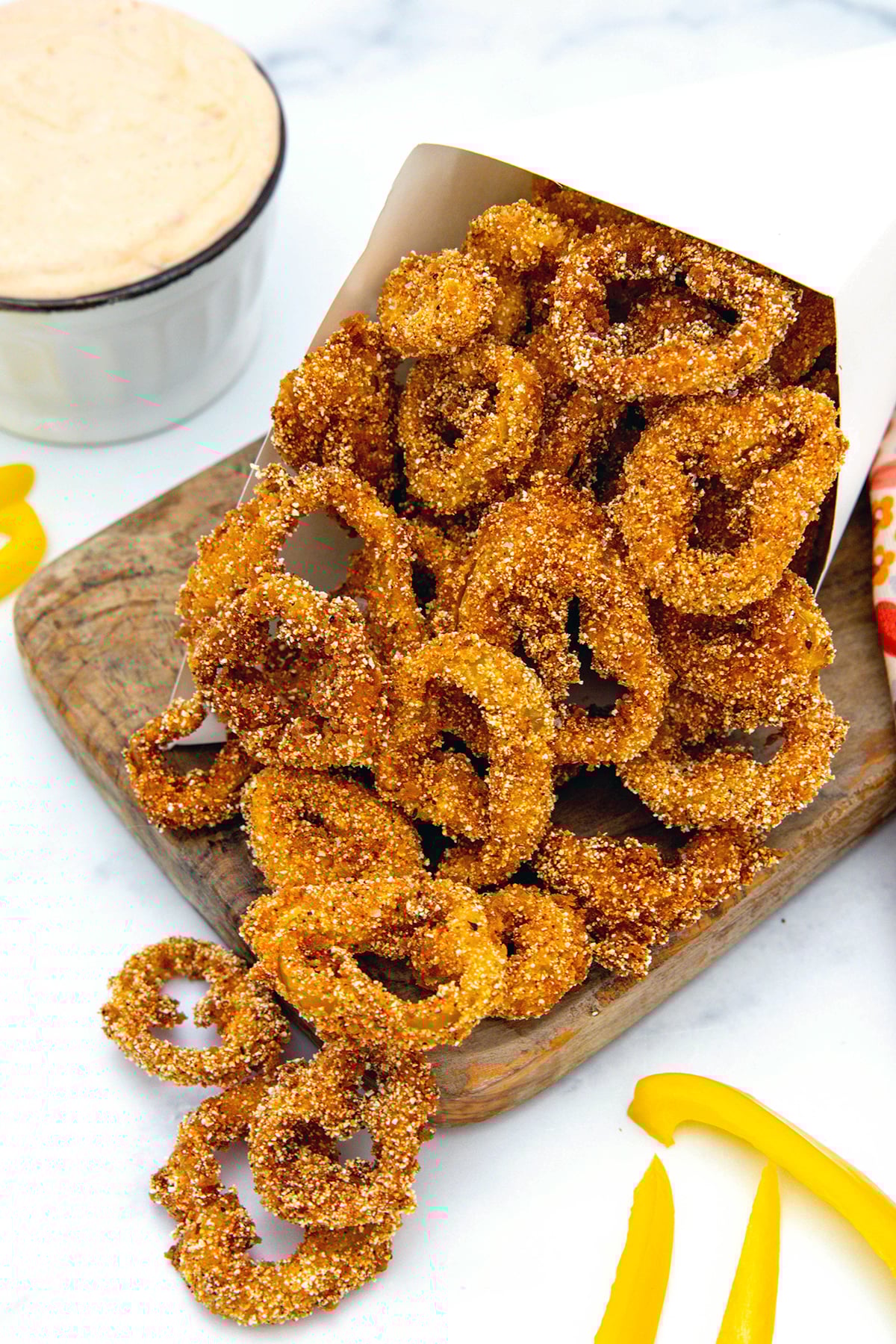 Fried banana pepper rings on a wooden board.