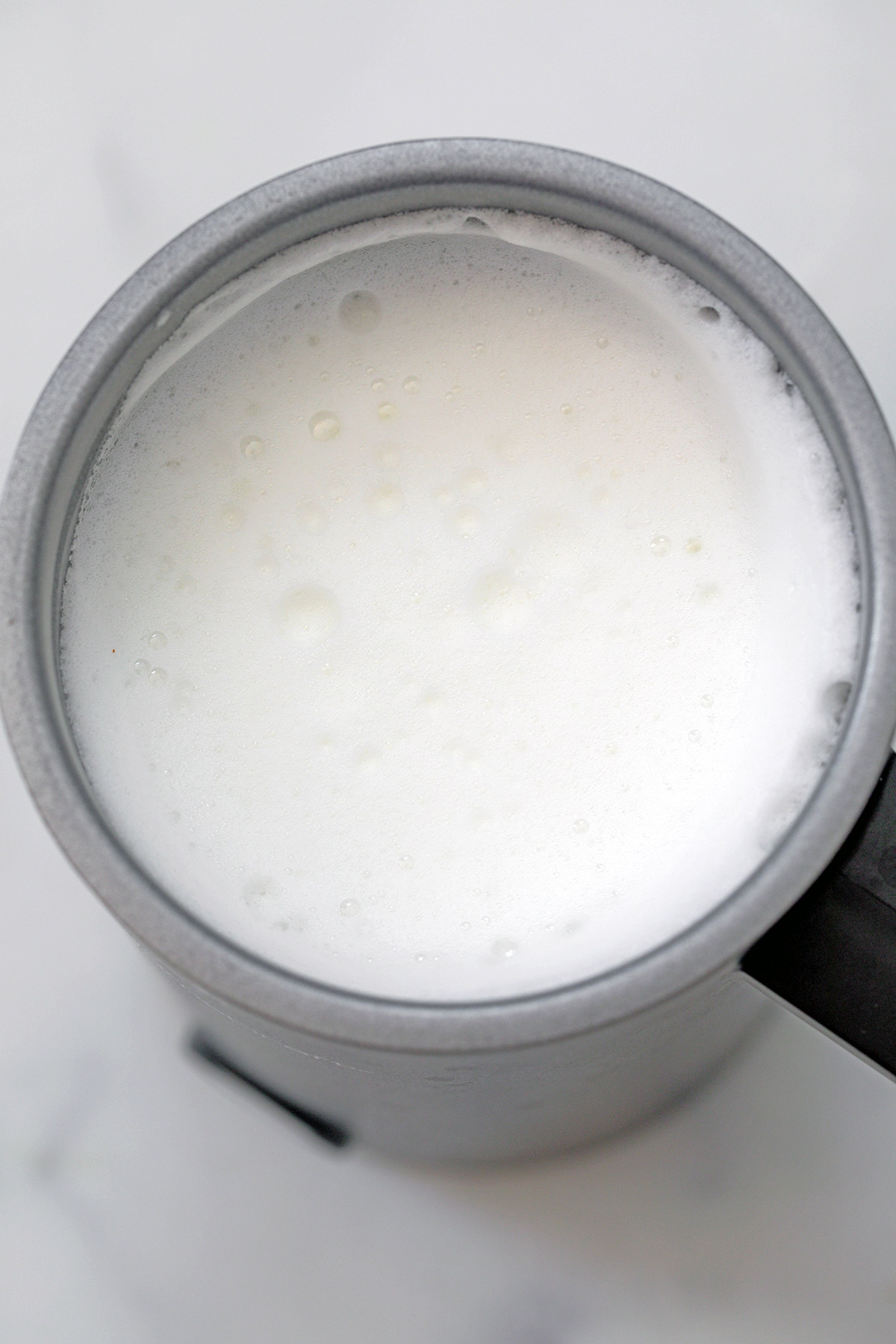 Frothed milk in electric frother.
