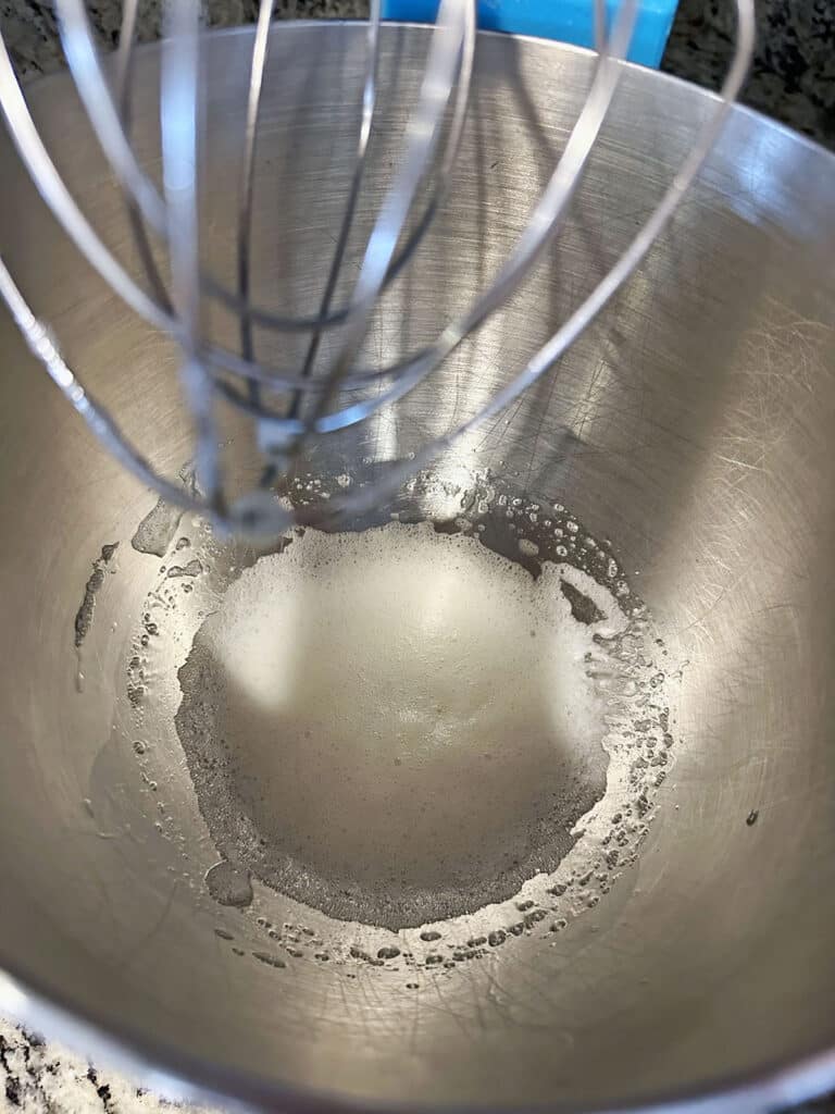 Foamy egg whites in mixing bowl with whisk beater.