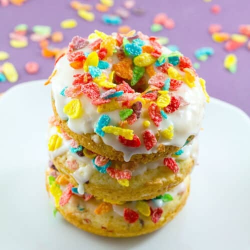 Stack of Fruity Pebbles donuts on a white plate.