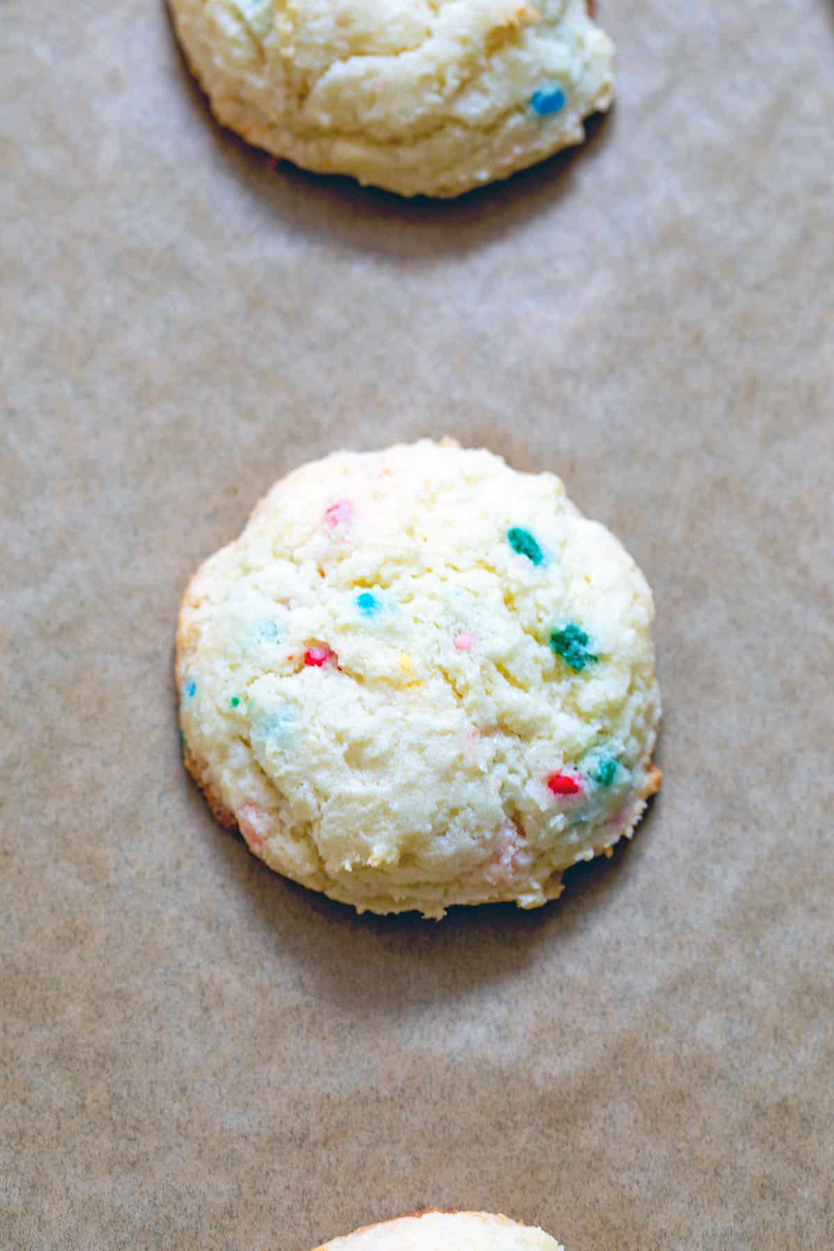 Funfetti cake mix cookies on a parchment paper-lined baking sheet just out of the oven.