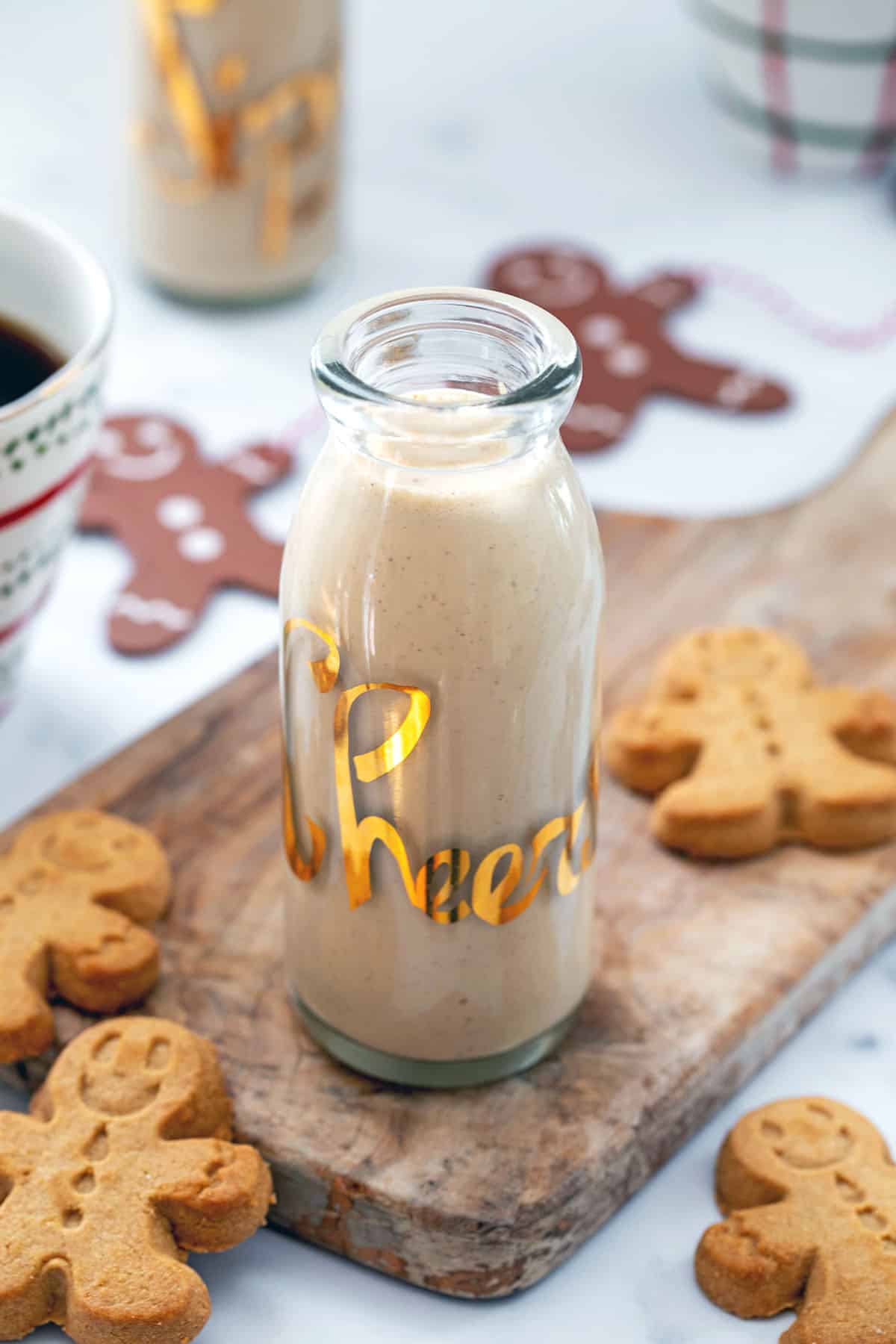 Overhead view of gingerbread coffee creamer in small carafe with gingerbread men cookies all around.