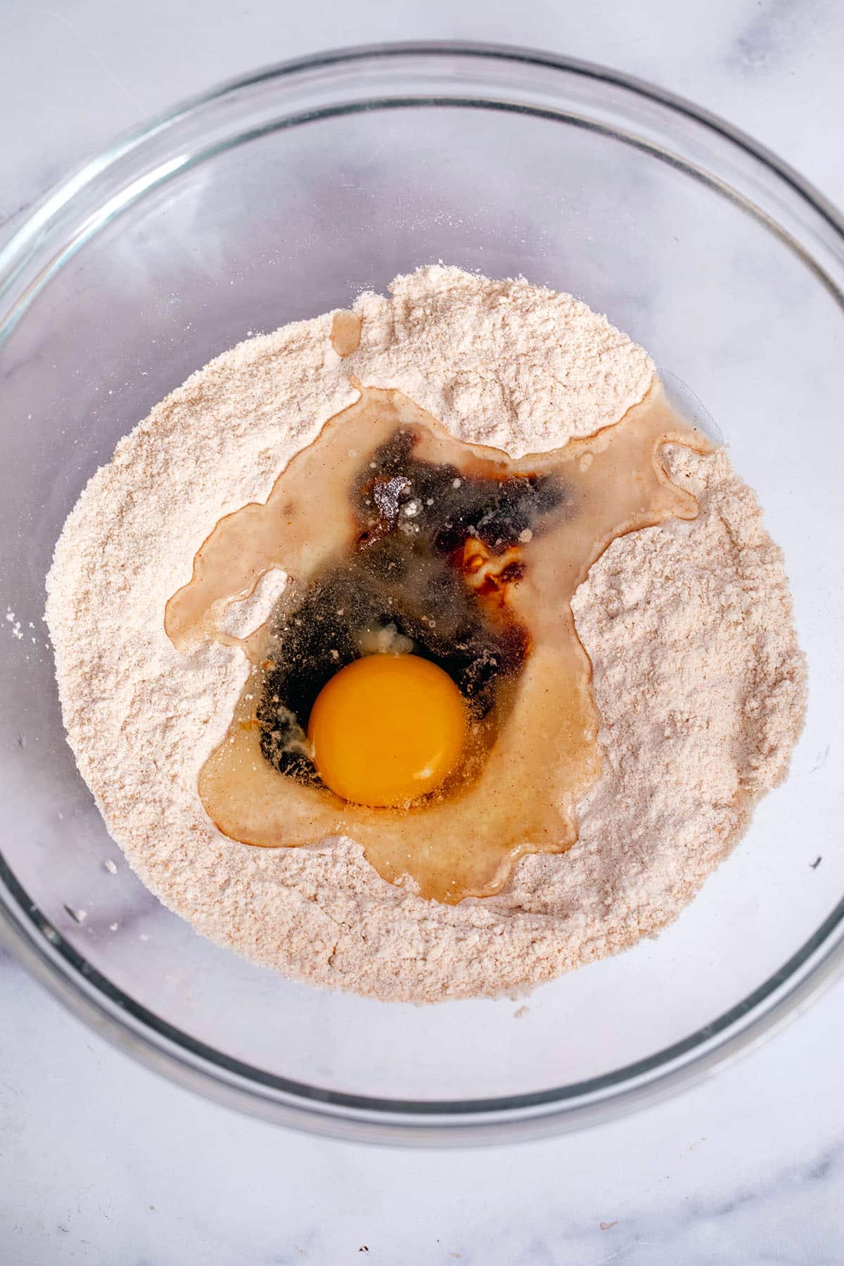 Whole wheat and all-purpose flour with eggs and molasses in mixing bowl.