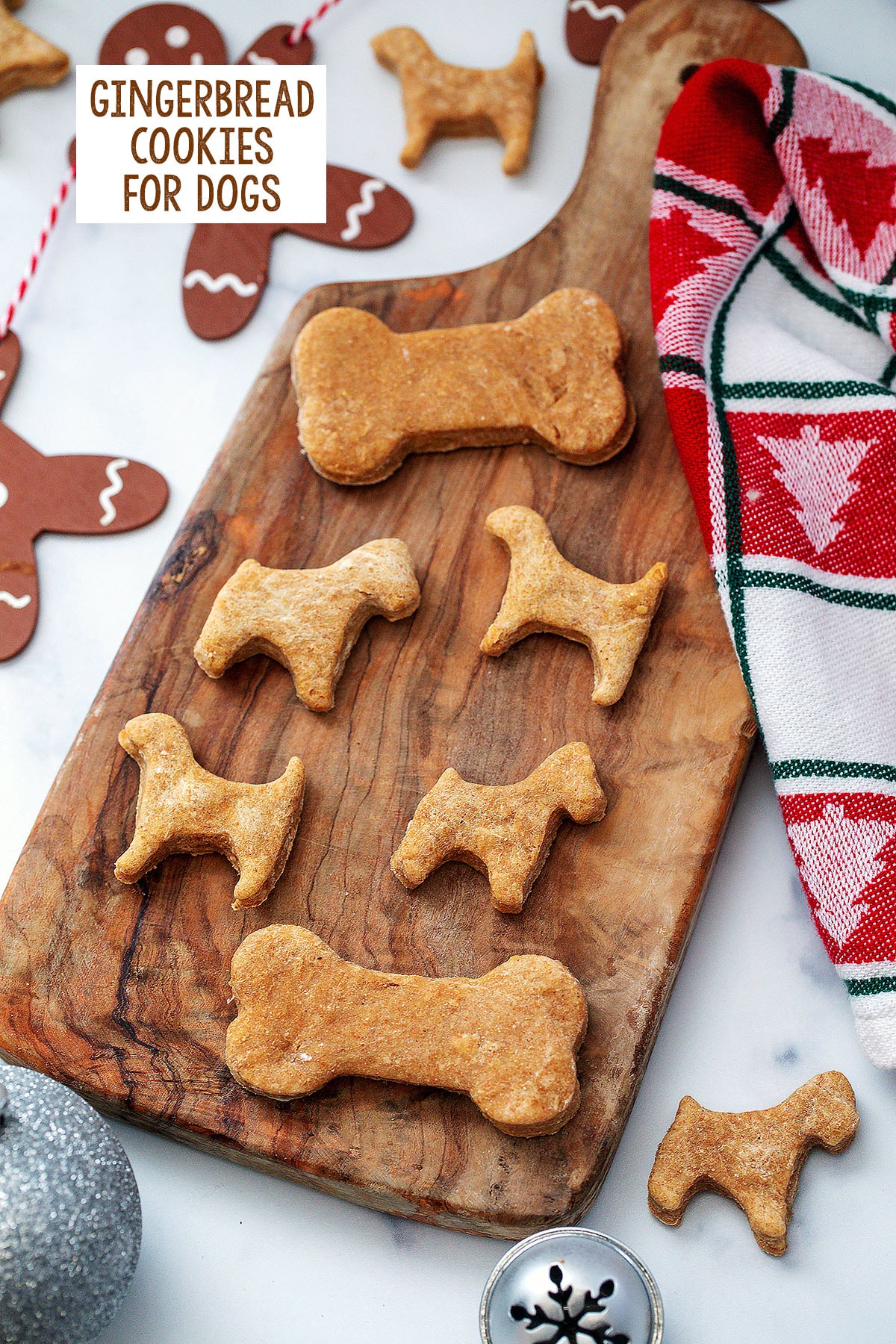 Overhead view of dog and bone shaped gingerbread cookies on a wooden board with recipe title at top.