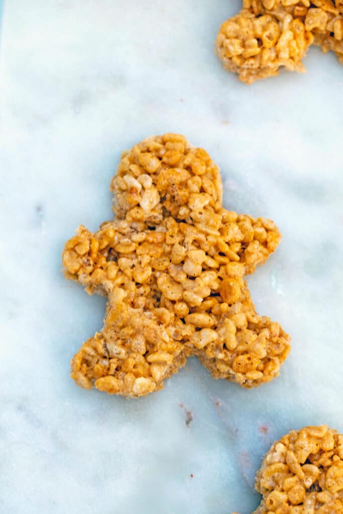 Rice Krispie treat shaped like a gingerbread man on marble surface.