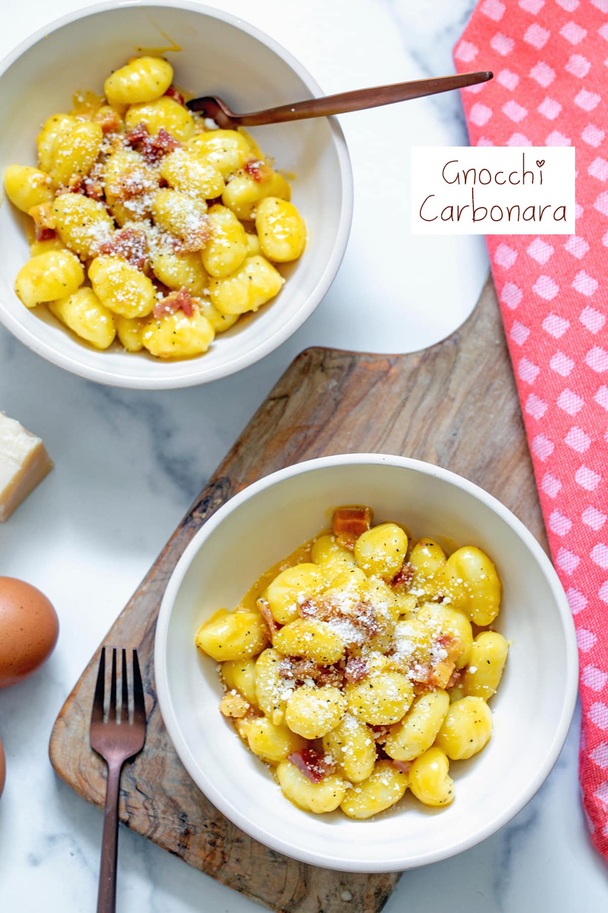 Overhead view of two bowls of gnocchi carbonara with recipe title at top.