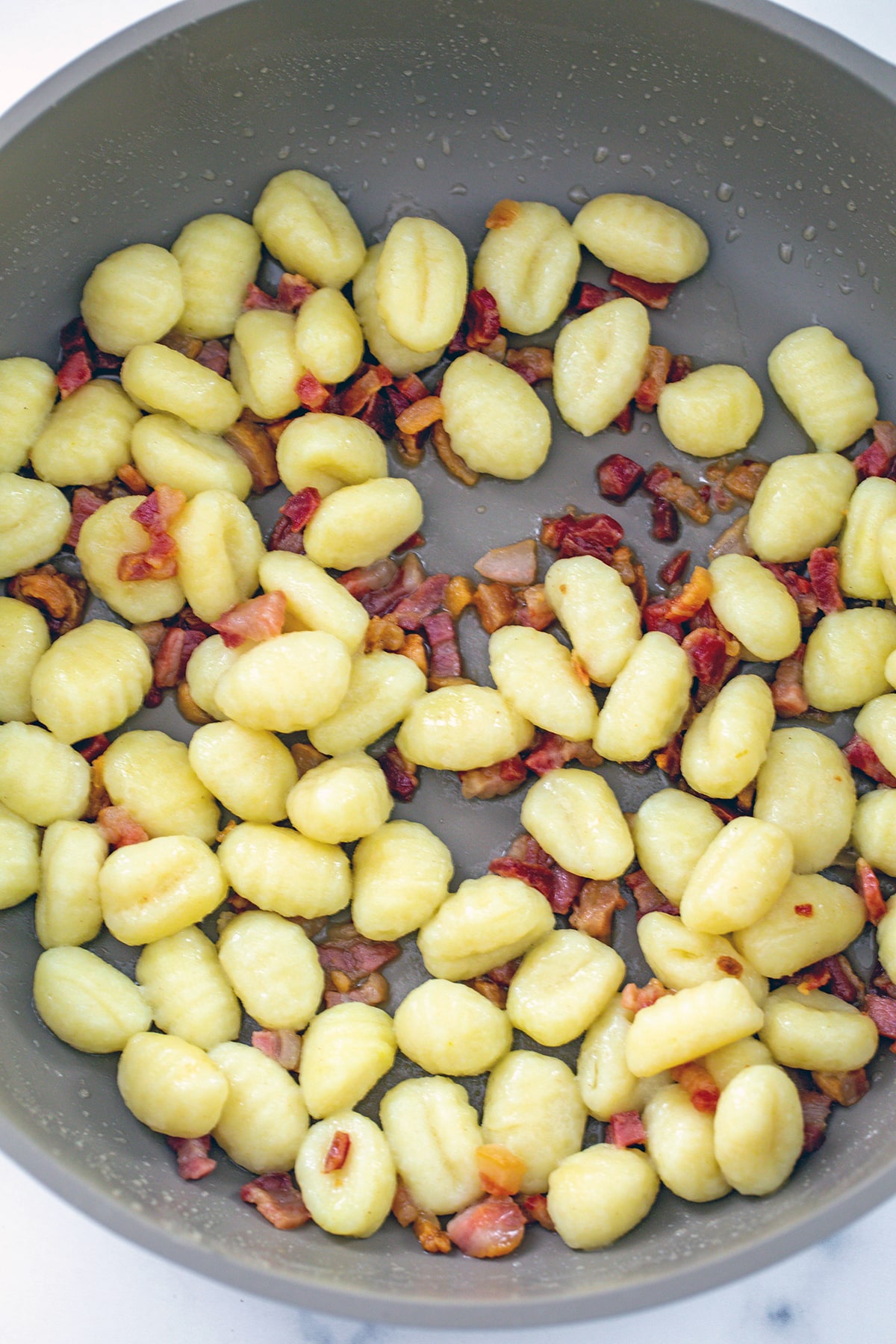 Gnocchi and pancetta in skillet.