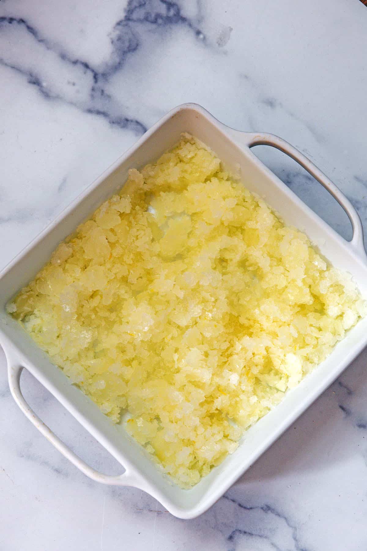 Lemonade granita in baking dish in the middle of freezing process.