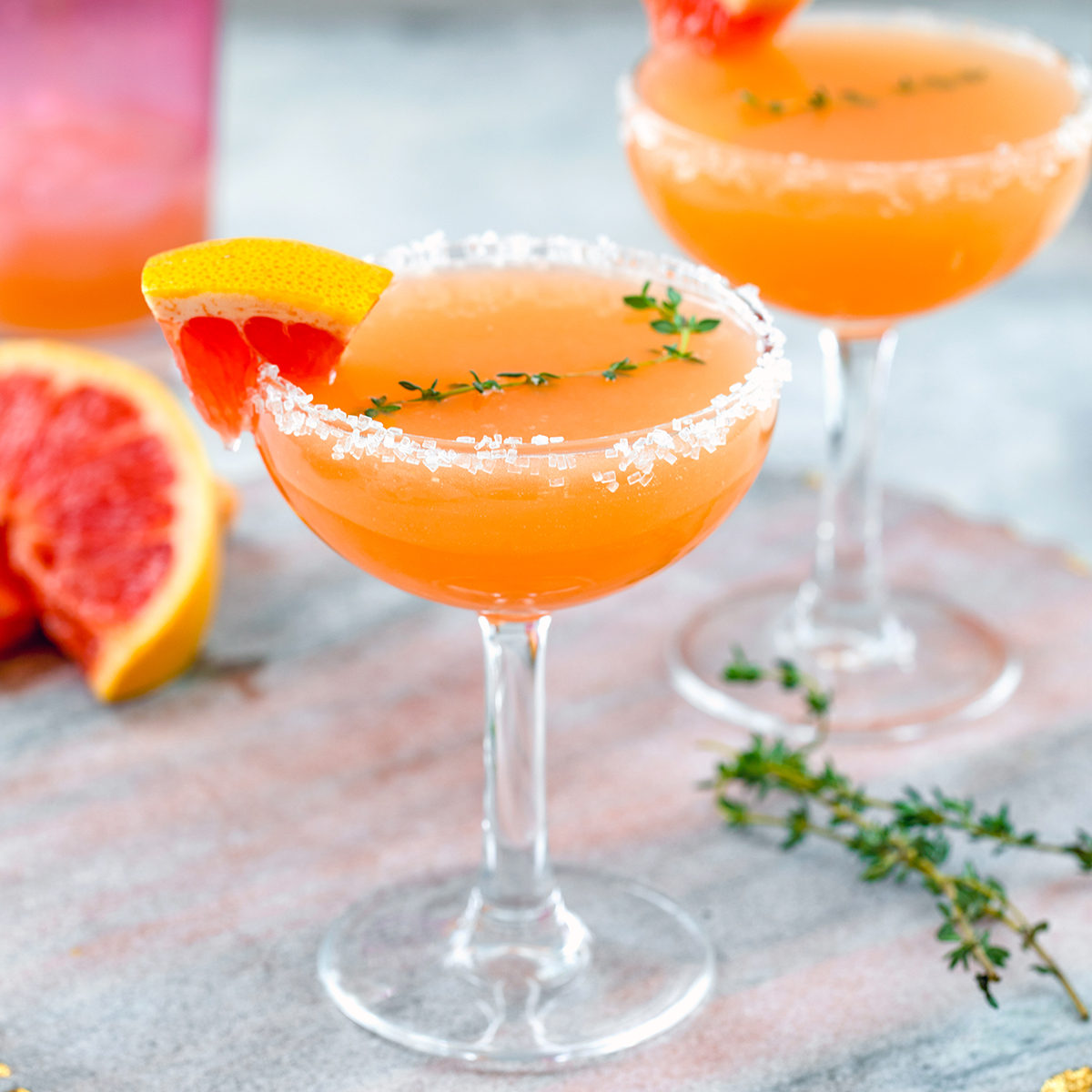 Closeup view of a grapefruit lillet cocktail with sprig of rosemary and grapefruit wedge.