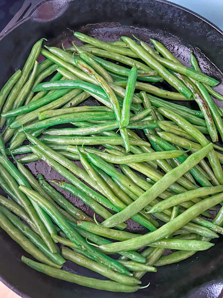 Green beans starting to blister in cast iron skillet.