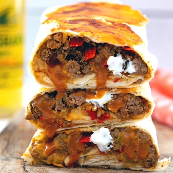 Closeup view of grilled cheese burritos stacked on each other with fillings.