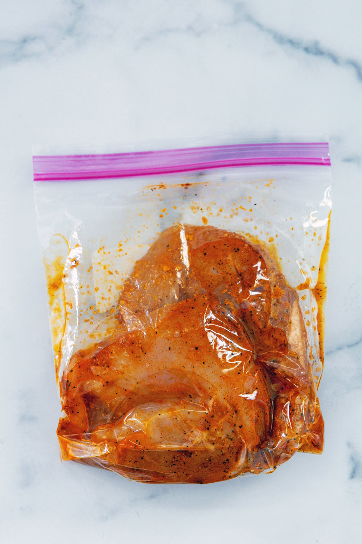 Chicken breasts in marinade in Ziplock bag.