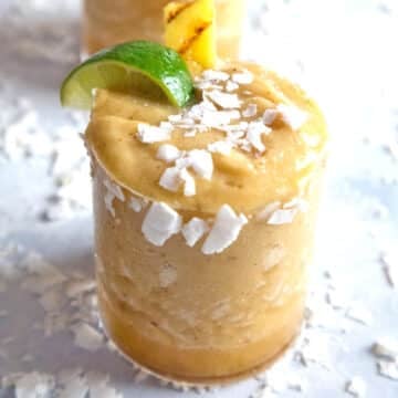 Closeup view of a grilled pineapple coconut margarita with coconut, lime, and pineapple garnish.