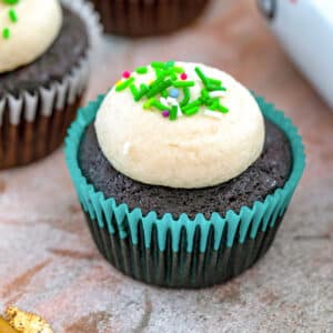Closeup view of a Guinness cupcake with Guinness frosting and green sprinkles.