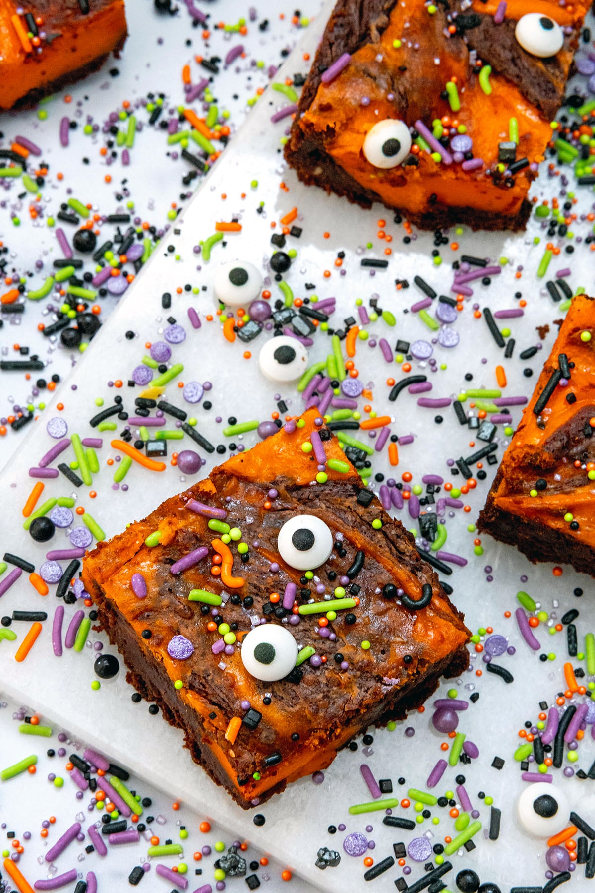 Overhead view of orange and black Halloween brownies with sprinkles and candy eyes all over.