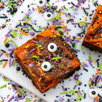 Closeup view of an orange and chocolate Halloween brownie with sprinkles and candy eyeballs.