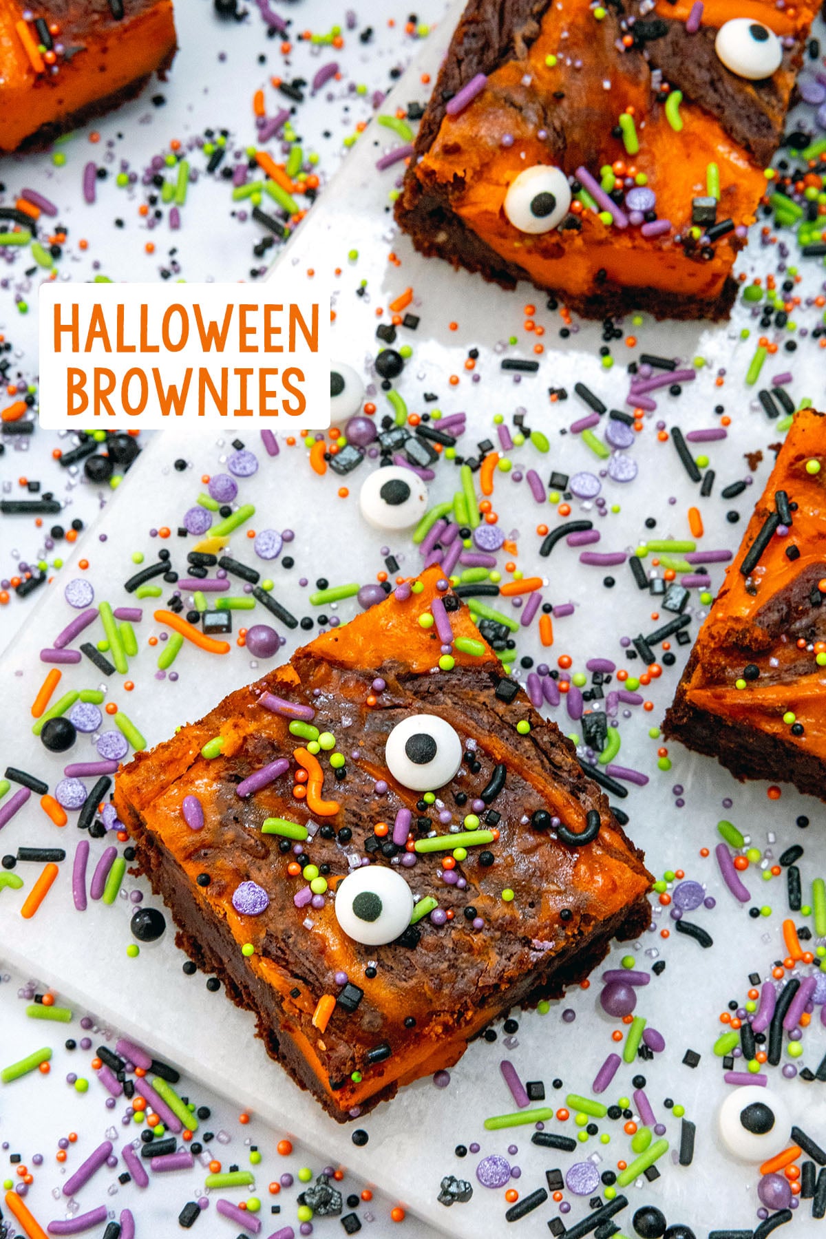 Overhead view of orange and black Halloween brownies with sprinkles and candy eyes all over and recipe title at top.