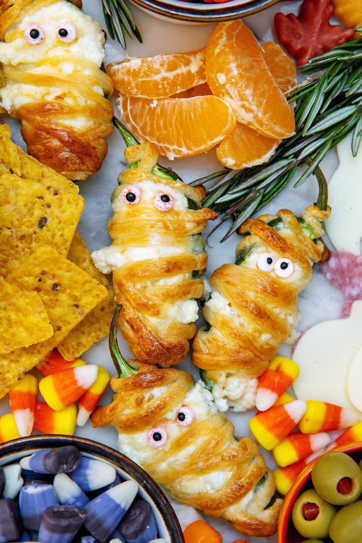 Closeup of jalapeño popper mummies on Halloween charcuterie board.