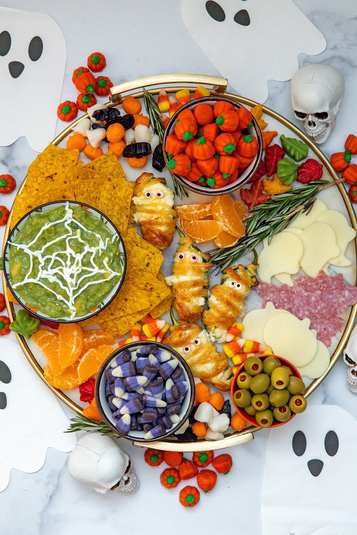Bird's eye view of Halloween charcuterie board with spiderweb guacamole, jalapeño popper mummies, candy, tortilla chips, cheese and salami, and more.