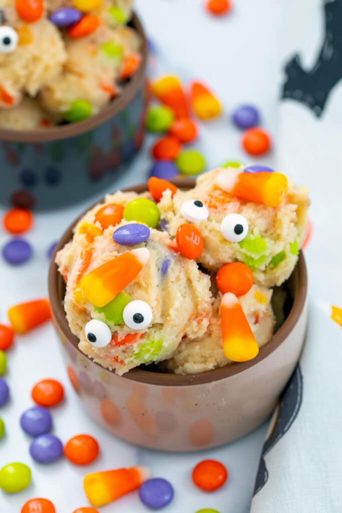 Halloween cookie dough in a bowl with candy corn, M&Ms, and googly eyes.