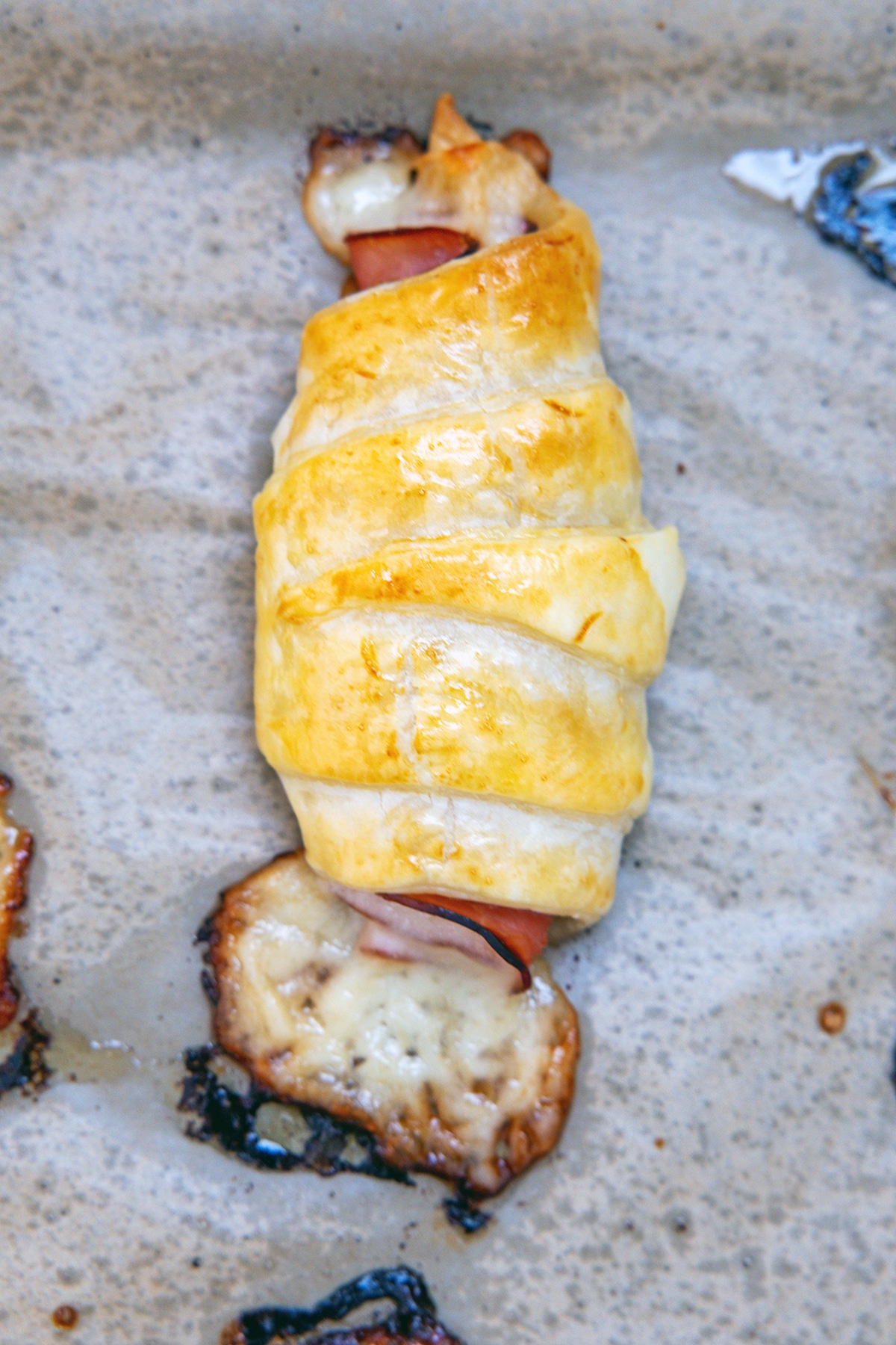 Closeup of a ham and cheese croissant baked on baking sheet.