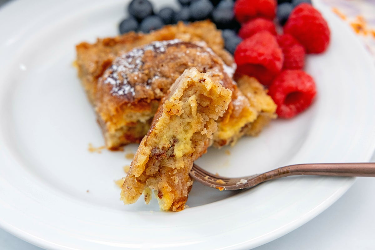 Landscape head-on view of a piece of Hawaiian roll french toast on a fork.