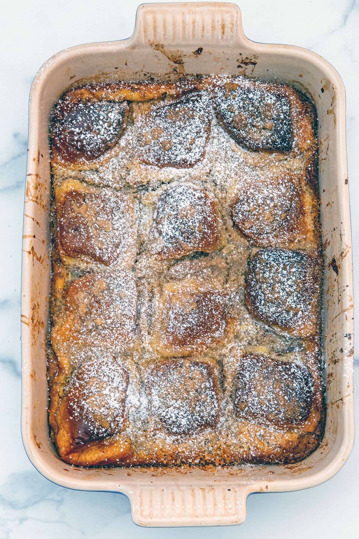 Overhead view of Hawaiian roll french toast casserole topped with powdered sugar.