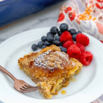 Closeup view of a slice of Hawaiian roll french toast casserole on a plate with berries.