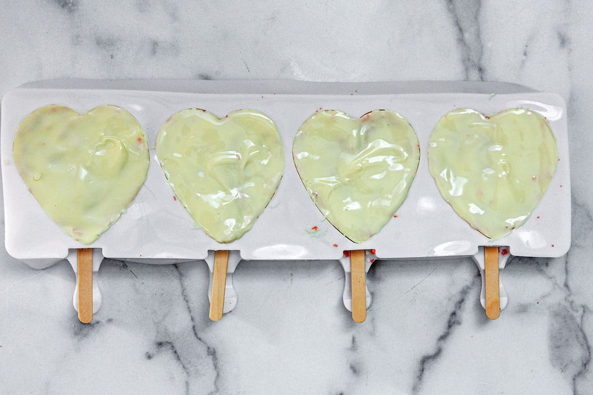 Melted white chocolate coated onto the back of cake on heart shaped mold.