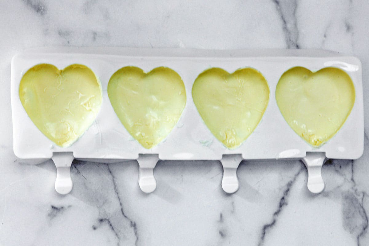 Melted white chocolate coating the inside of heart-shaped molds.