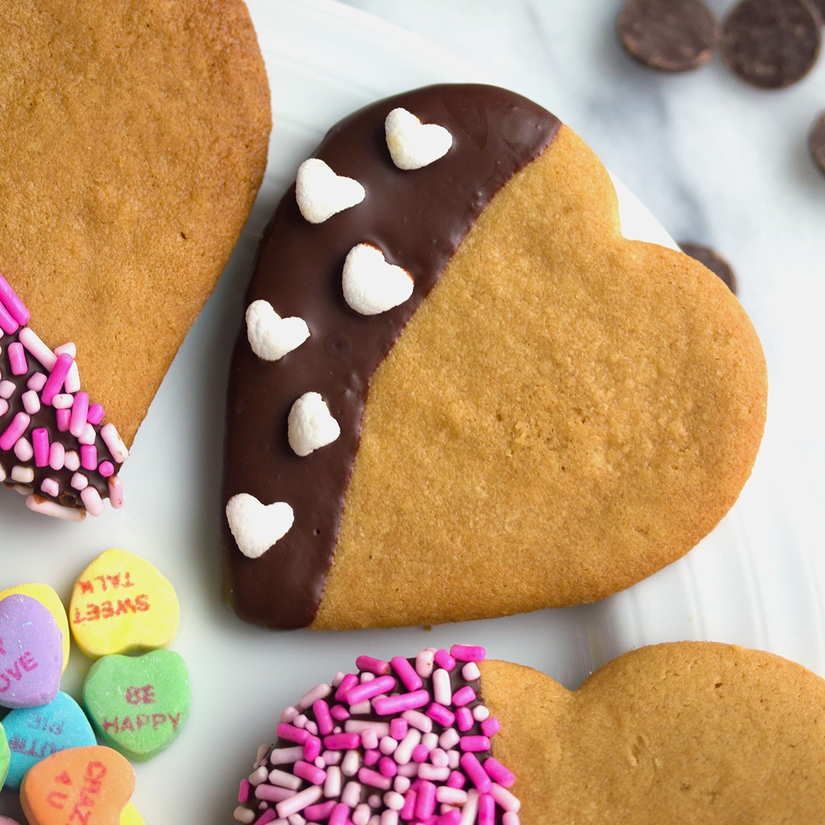 Closeup view of heart-shaped peanut butter cookies dipped in chocolate with sprinkles.