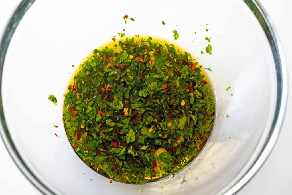 Herbs and olive oil mixed together in bowl.