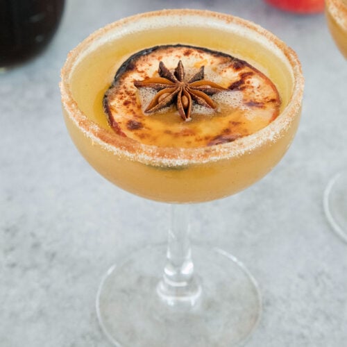 Closeup view of a honeycrisp apple cocktail with apple and star anise garnish.