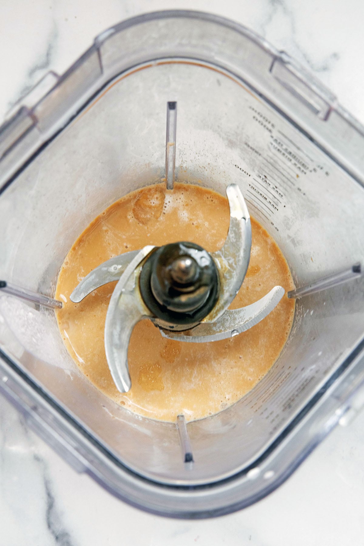 Overhead view of milk, espresso, and syrup in a blender.