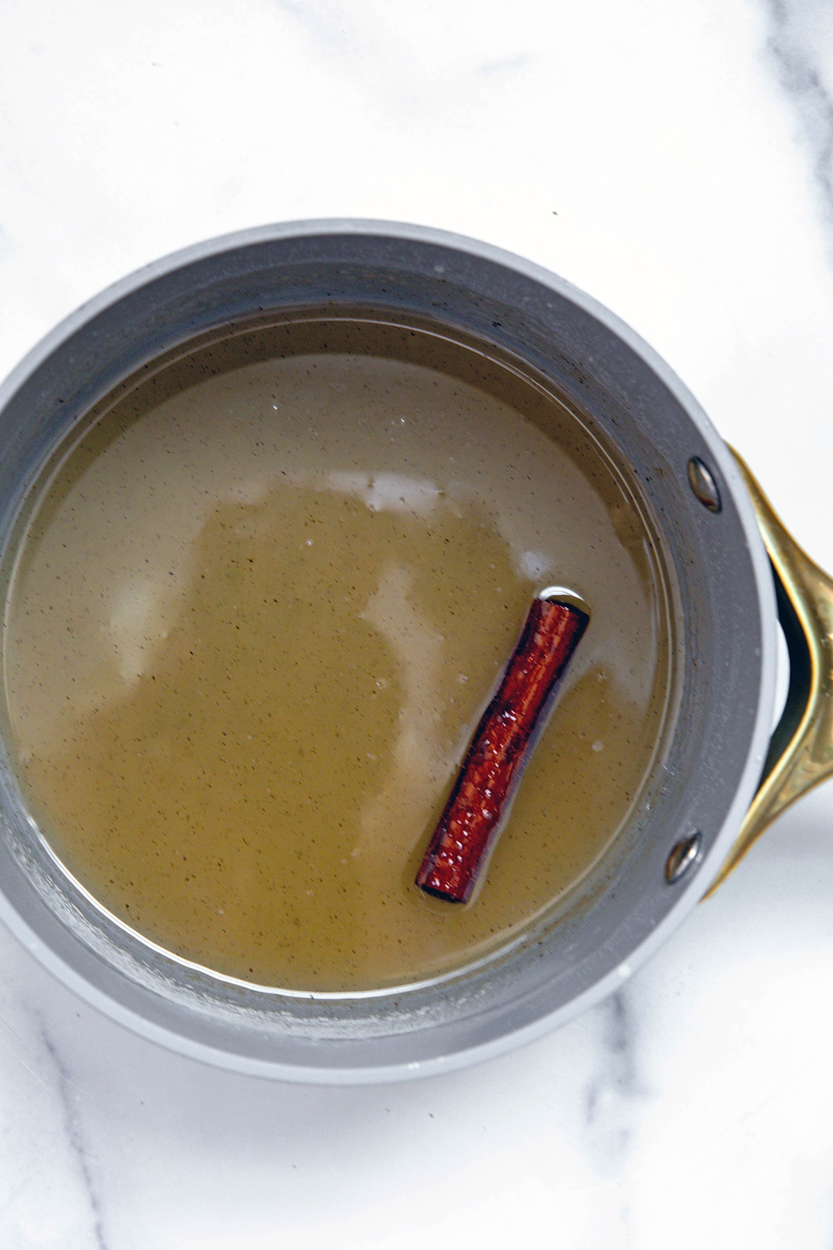 Horchata syrup in saucepan with cinnamon stick.