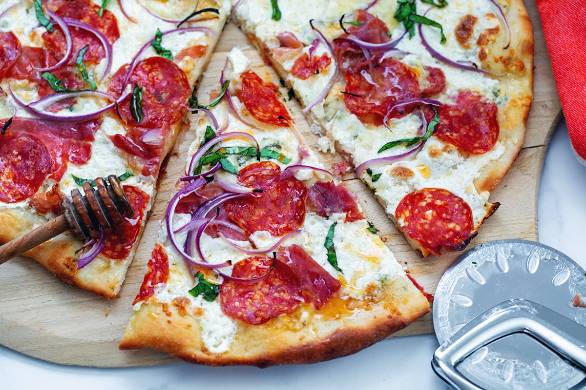 Landscape overhead view of hot honey pizza with pizza slicer.