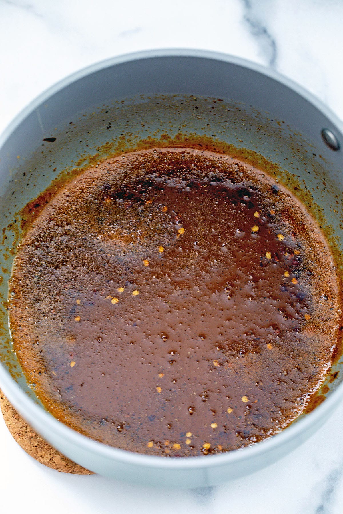 Hot honey sauce simmering in saucepan.