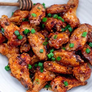 Overhead closeup view of hot honey wings topped with scallions.