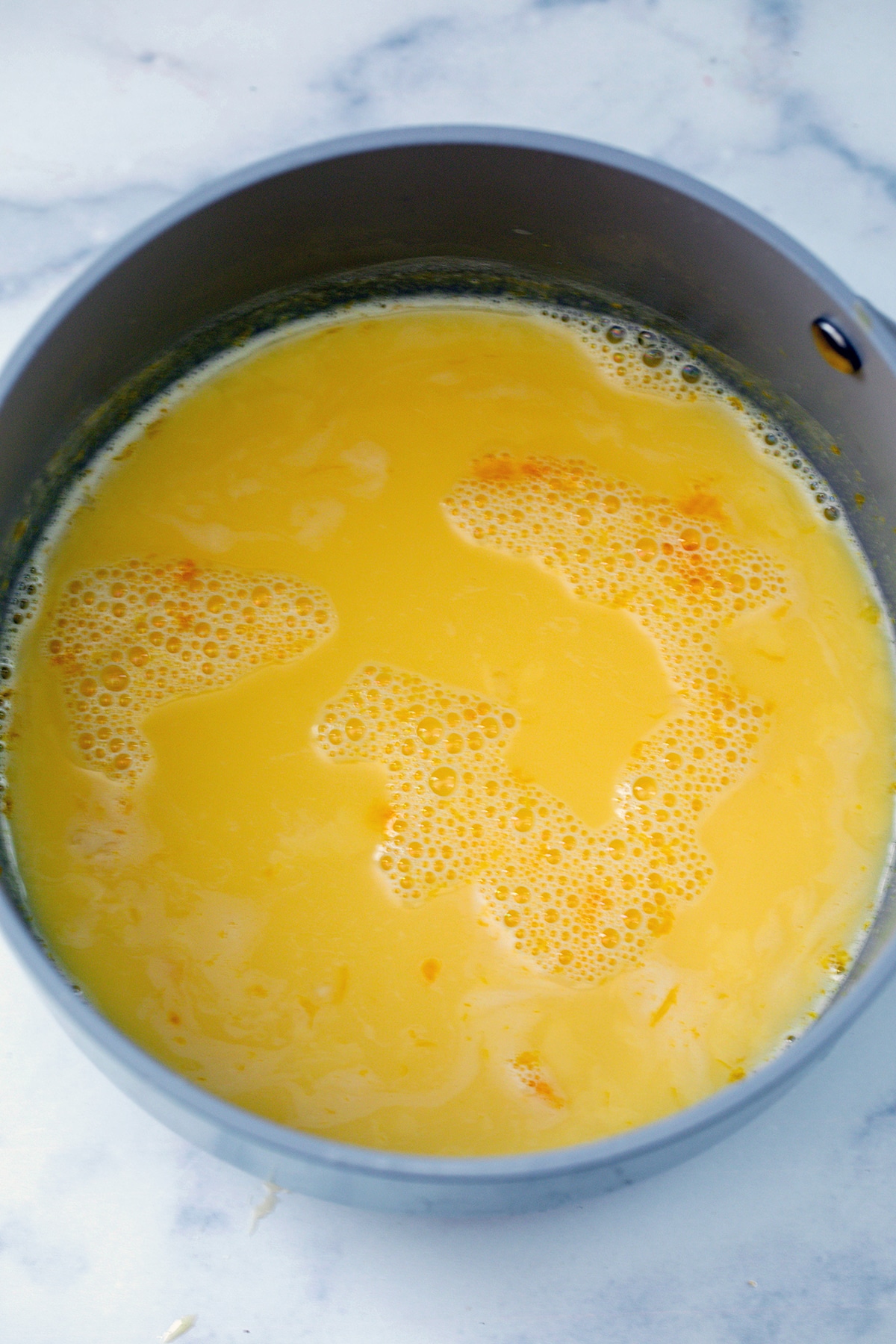 Tempered eggs in milk in saucepan.