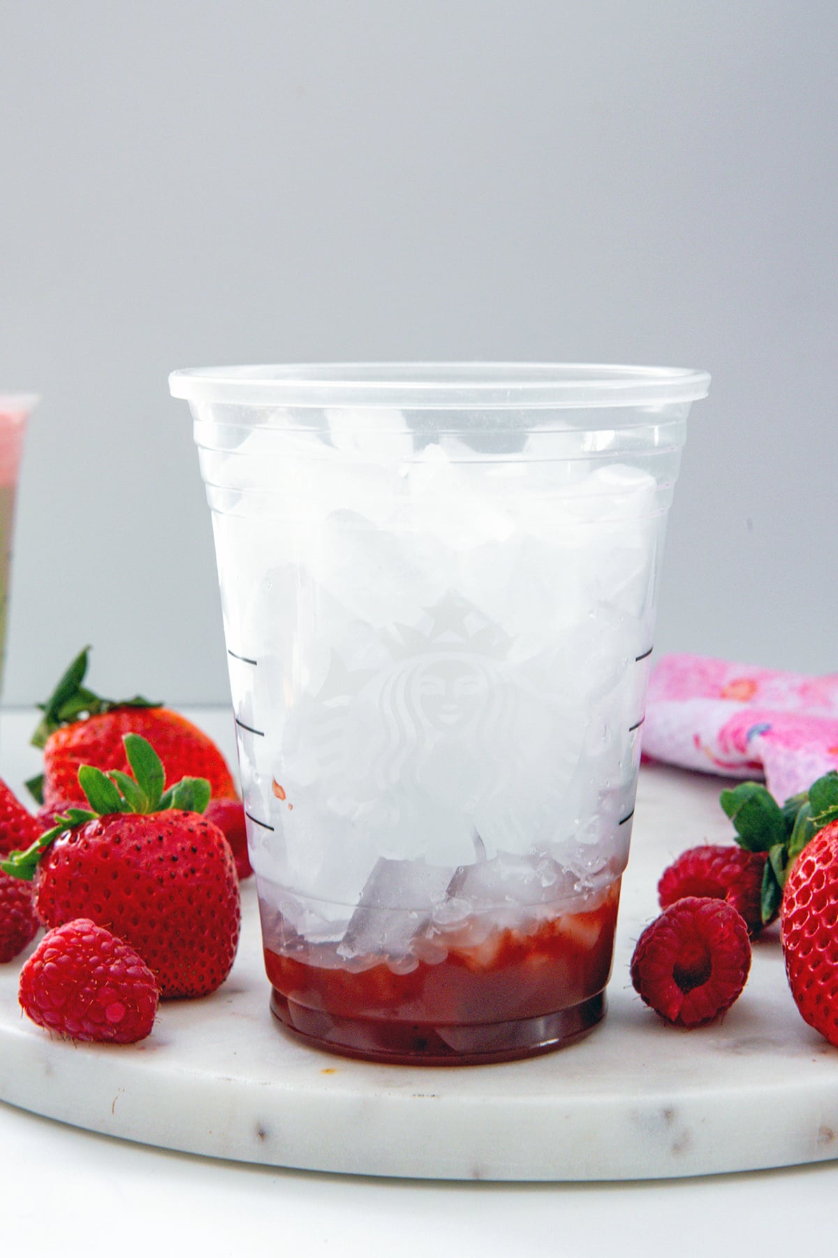 Starbucks cup filled with ice with strawberry puree on the bottom.