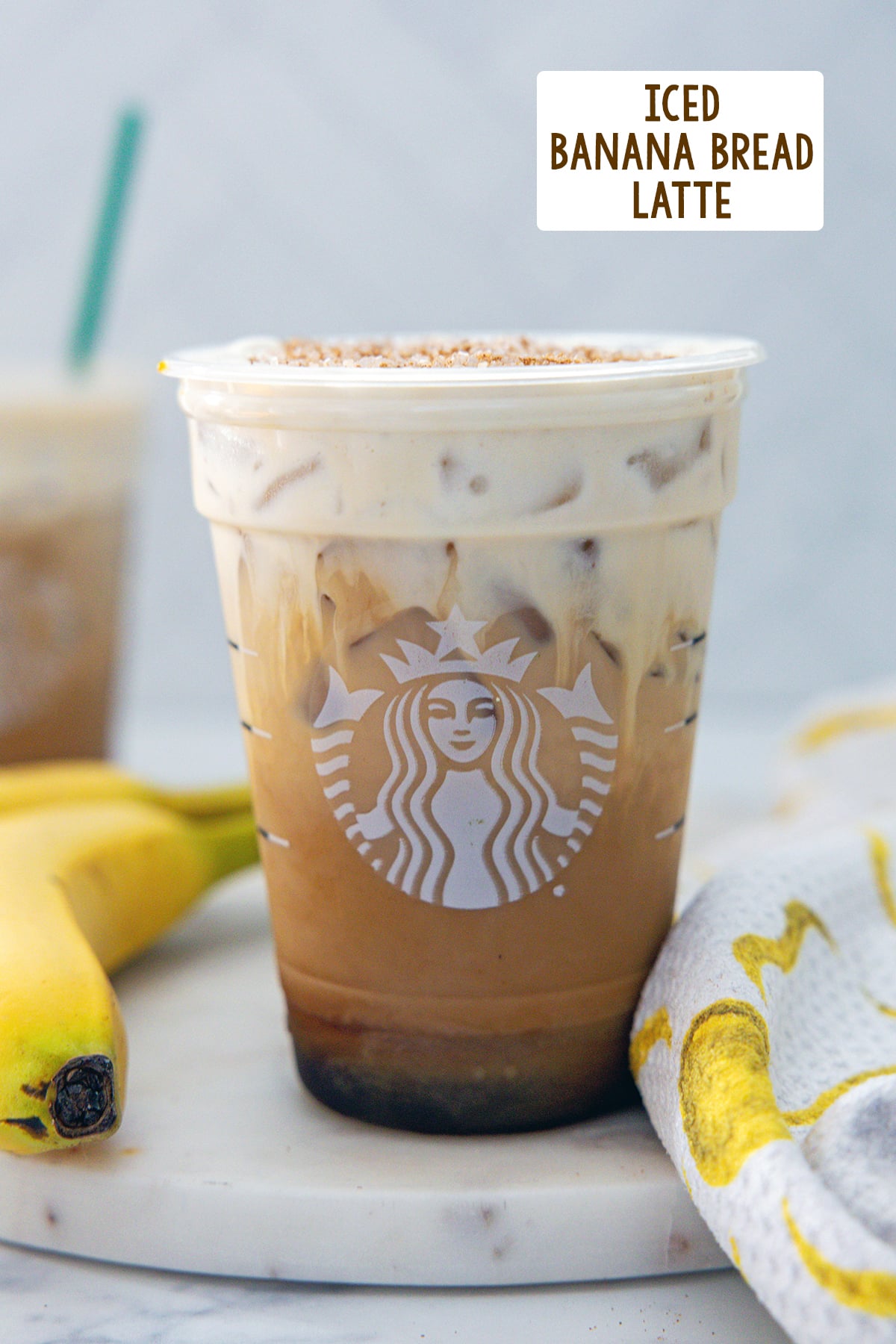 Head-on view of an Iced Banana Bread Latte with bananas in the background and recipe title at top.